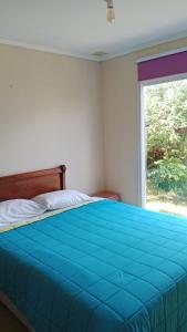 una camera da letto con un letto blu con una finestra di Casa Amayita 2 a Puerto Varas