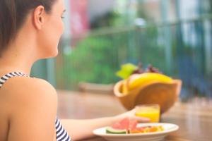 a woman sitting at a table with a plate of food and a drink at Coral Tree Inn in Cairns