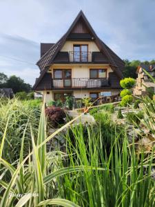 a house seen through the tall grass at Urocze Gniazdko pod Tatrami in Ratułów