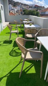 a row of tables and chairs on a balcony with green grass at Urban Hostel Mindelo in Mindelo