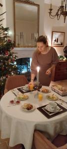 a woman lighting a candle at a table with food at Chambres d'hôtes Le Griffon 1855 in Saint-Laurent-des-Autels