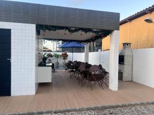 a patio with chairs and a table and umbrella at Quarto lovina e fest verão in Cabedelo