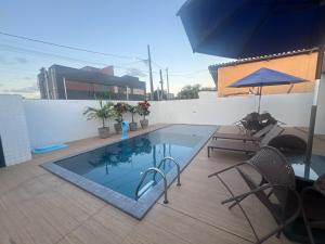 a swimming pool on a patio with chairs and an umbrella at Quarto lovina e fest verão in Cabedelo