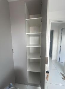 a closet with white shelves in a room at Quarto lovina e fest verão in Cabedelo