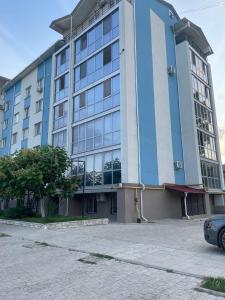 ein blau-weißes Gebäude mit einem davor geparkten Auto. in der Unterkunft Spacious apartment with a beautiful view in Căuşeni