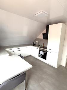 una cucina bianca con armadietti e elettrodomestici bianchi di Helles & Modernes Apartment in Heilbronn a Heilbronn