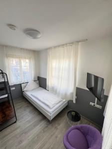 ein kleines Zimmer mit einem Bett und einem Fernseher in der Unterkunft FlyInn-Pension Airport-Messe in Leinfelden-Echterdingen