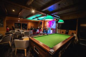 a room with a pool table in a room with chairs at Hotel Emeraude in Peisey-Nancroix