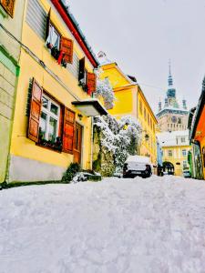 Una calle cubierta de nieve con edificios y un coche. en Casa Hermann, en Sighişoara
