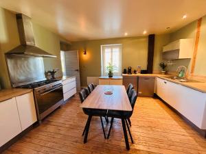 a kitchen with a wooden table and chairs in it at Gîte de l'auberge in Lupé