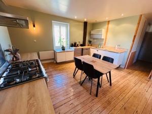 a kitchen with a table and a stove in a room at Gîte de l'auberge in Lupé +5 photos