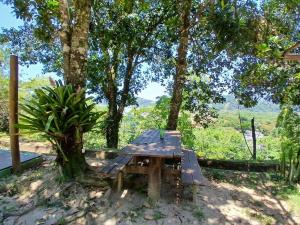 a picnic table in the shade of a tree at Camburi Chalet - por do sol in São Sebastião