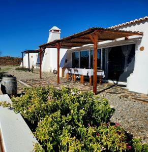 a house with a pavilion with a lighthouse in the background at Natur Amêndoa in Odeleite