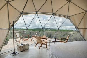 a tent with chairs and a bed and a table at Bodega Alpasión Lodge y Glamping in Tunuyán