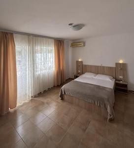 a bedroom with a bed and a large window at Casa Silvia in Costinesti