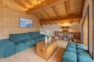 a living room with a blue couch and a table at Chalet APY - Grand chalet neuf avec terrasse, 6 chambres en-suite , wifi, balcon, etc in Les Gets