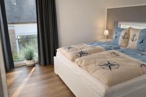 una camera da letto con due letti e una grande finestra di HausLIEBLINGSPLATZ - am Meer - Luxus Villa mit 4 Schlafzimmern, 3 Badezimmern Sauna, Kamin, Weber-Grill und Wallbox a Dranske Altre 21 foto