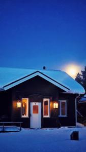 una casa con il tetto coperto di neve con una luce di Riverfront Aurora Chalet a Kiruna