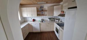 een kleine keuken met witte kasten en witte apparaten bij Fihermans House Joanna in Hirtshals