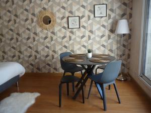 een tafel en stoelen in een kamer met een muur bij Au gré des marées, 2 chambres in Hanvec