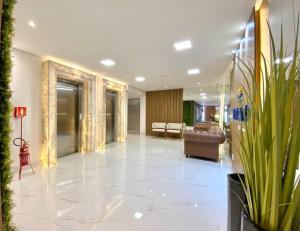 a lobby with a chair and a couch and some plants at Studio Capão - novo com piscina e rooftop in Capão da Canoa +21 photos
