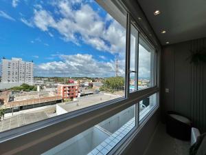 a large window in a room with a view of a city at Studio Capão - novo com piscina e rooftop in Capão da Canoa
