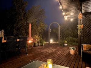 a wooden deck with chairs and a table with lights at Salmon River Cabin in Þingeyjarsveit