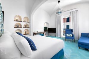a bedroom with a white bed and blue chairs at Grand Hotel Europa Palace Sorrento in Sorrento