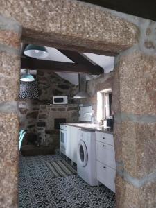 a kitchen with a washer and dryer in a stone wall at Casa da Figueira in Guilhufe