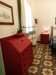 een kamer met een rode commode, een bed en een raam bij La Casa Vecchia in Nuraminis