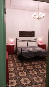 een slaapkamer met een bed met 2 nachtkastjes en een kroonluchter bij La Casa Vecchia in Nuraminis