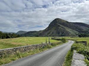 a dirt road with a mountain in the distance at Y Mor Cosy Apartment in Tywyn