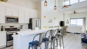 a kitchen with white cabinets and a bar with stools at Strand Way A B by AvantStay in Oceano