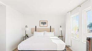 a white bedroom with a large bed and a window at 2 Coastal Studios at Cayucus Beach Access Ocean Views in Cayucos