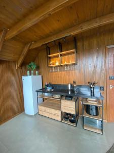 a kitchen with a counter and a refrigerator at Refúgio na Rocha - Chalé in Palhoça