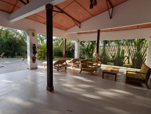 een woonkamer met stoelen en tafels op een patio bij Flower Garden House in Sanyang