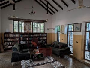 een bibliotheek met banken en een tafel en boekenplanken bij Flower Garden House in Sanyang