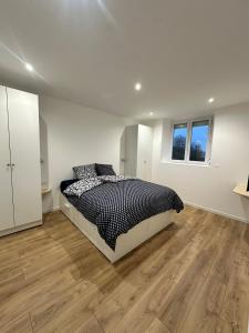 a white bedroom with a bed and a wooden floor at Maison de ville a Berck in Berck-sur-Mer