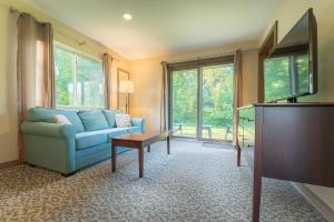 a living room with a blue couch and a tv at Sun & Ski Inn and Suites in Stowe