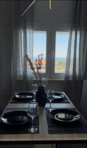 einen Tisch mit Tellern und Gläsern und eine Vase mit Blumen in der Unterkunft Olympus Embrace in Leptokaryá