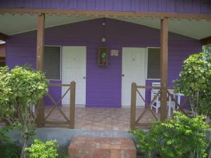 a purple house with a white door at Ansells Thatch Walk Cottages in Negril