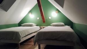 two beds in a room with a green wall at La Grange de Pépé in Biltzheim