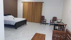 a bedroom with a bed and two chairs at Orion Blue Hotel in Dombagahawatta