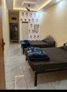 three beds in a room with purple flowers on the wall at KeshavShree home stay in Ujjain +1 photo