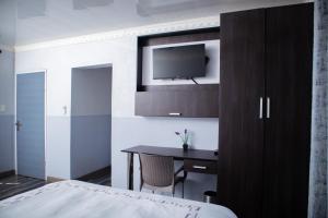 a bedroom with a bed and a desk and a tv at Noble Hearts Bed & Breakfast in Maseru