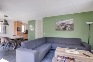 a living room with a blue couch and a table at 6 - Person Lake Area 28 Bungalow in Ewijk