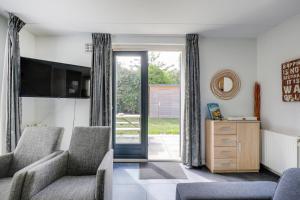 a living room with two chairs and a sliding glass door at 6 - Person Lake Area 28 Bungalow in Ewijk