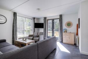 a living room with a couch and chairs and a clock at 6 - Person Lake Area 28 Bungalow in Ewijk +35 photos