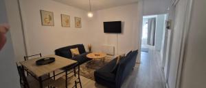 ein Wohnzimmer mit Tisch, Stühlen und Fernseher in der Unterkunft Blue K in Saint-Claude