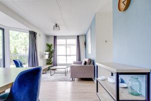 a living room with a table and blue chairs at 4 - Person Lakeside 47 Bungalow in Ewijk